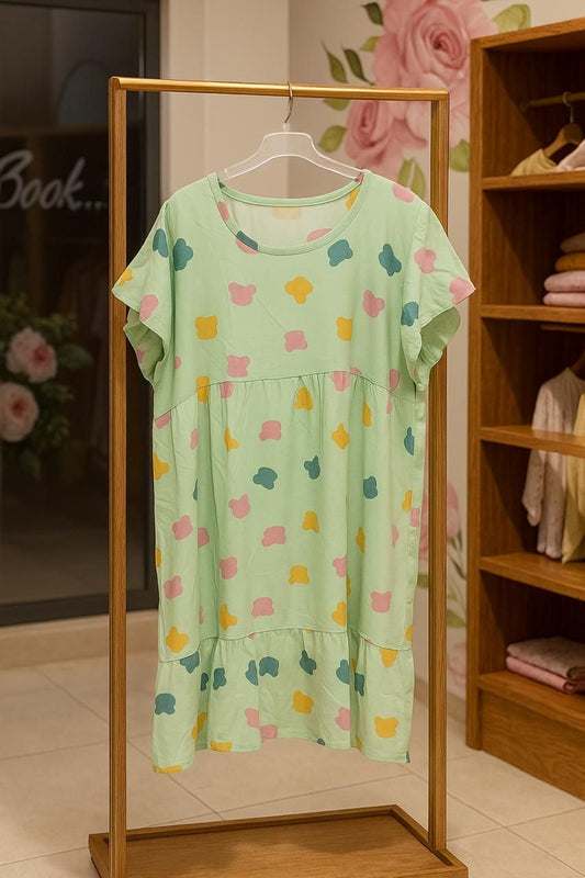 Green dress with colorful patterns on a hanger against a wooden shelf background