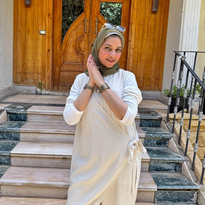 Woman in a hijab standing on steps with a wooden door in the background
